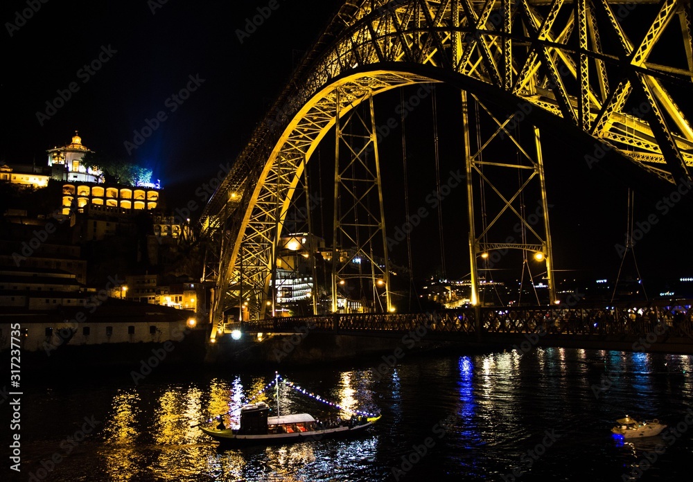 Fototapeta premium Portugal, evening Porto, lights of night city, night view of The Eiffel Bridge, Ponte Dom Luis, Bridge Ponti Di Don Luis, Boat floats under the bridge at night, Douro river, Porto by the river