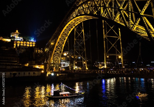 Portugal, evening Porto, lights of night city, night view of The Eiffel Bridge, Ponte Dom Luis, Bridge Ponti Di Don Luis, Boat floats under the bridge at night, Douro river, Porto by the river