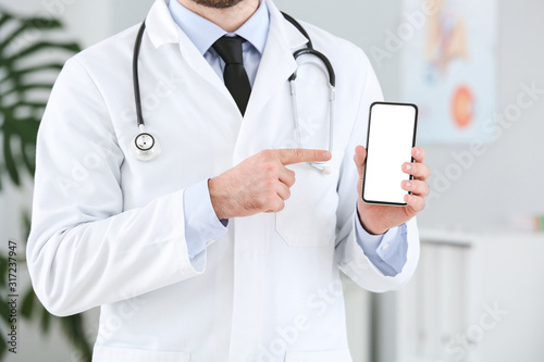 Male doctor with mobile phone in clinic