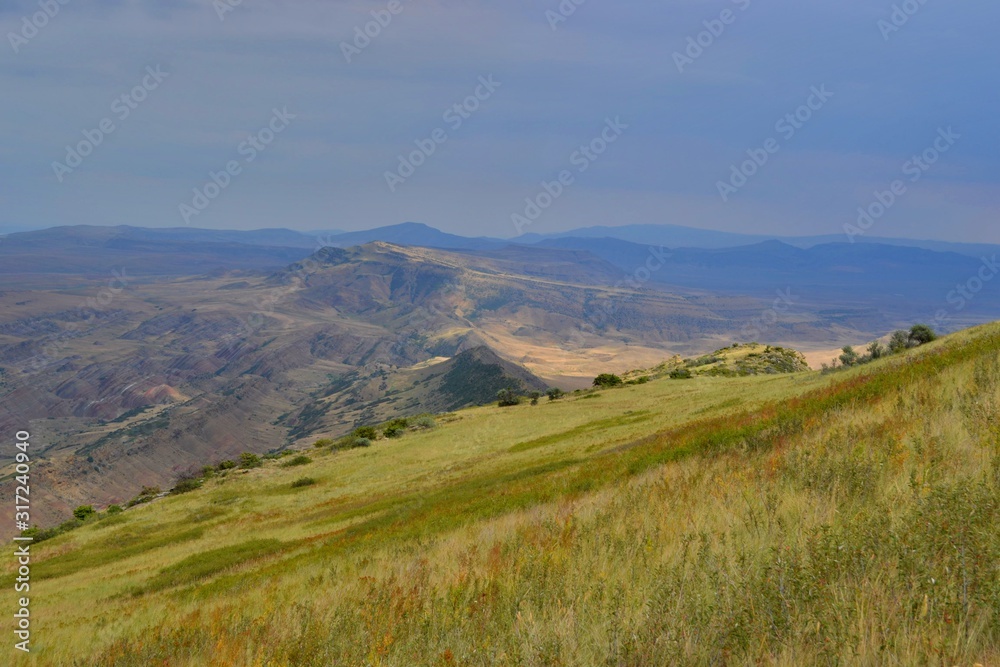 Half-desert on the border of Georgia with Azerbaijan. Brown land with small green bushes, gray clouds, blue sky. Half-desert on the border of Georgia with Azerbaijan. Brown land with small green bushes, gray clouds, blue sky.