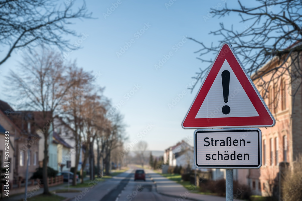 Verkehrsschild mit Warnhinweis auf Straßenschäden in deutscher Sprache