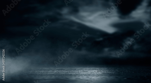 Dramatic black and white background. Cloudy night sky, moonlight, reflection on the pavement. Smoke and fog on a dark street at night. © MiaStendal