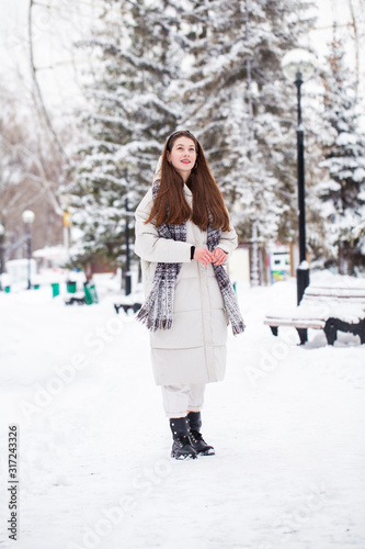 Young brunette woman in white down jacket in winter street