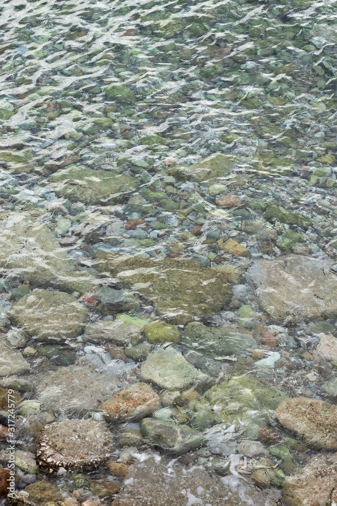 abstract sea background with water covering stones and pebbles. Vertical orientation