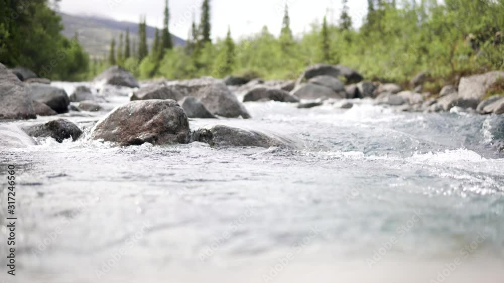 A stormy stream of river carving its way through the mountain valley. 