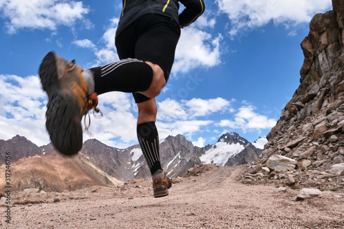 Closeup of feet with running shoes of a trailrunner man running in the mountains trail