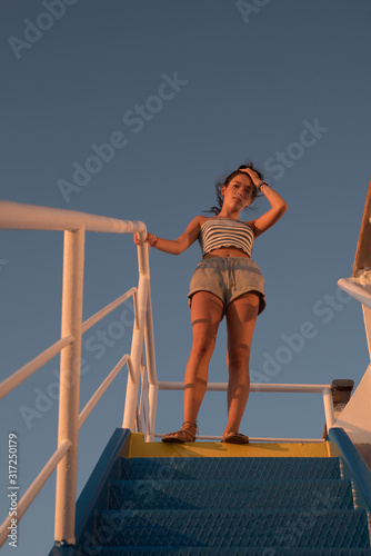 Asian teen standing on top of blue stair with yellow stripe