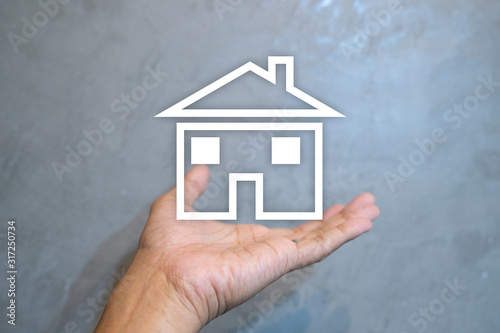 Hand holding house on the cement wall loft background