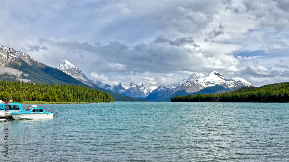 The picturesque mountain Maligne Lake in the Jasper National Park. A pier with boats on the lake and a sunny summer day