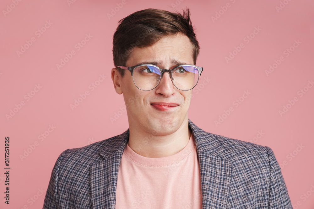 Boy in glasses isolated over pink wall background.