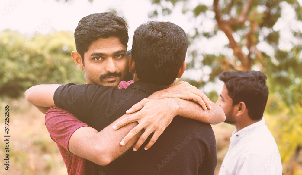 Concept of fake hug, friendship, embracing - Young Hypocritical boy embracing a friend at outdoors - Friend hugging and looking at camera Concept of fake hug, friendship, embracing - Young Hypocritical boy embracing a friend at outdoors - Friend hugging and looking at camera