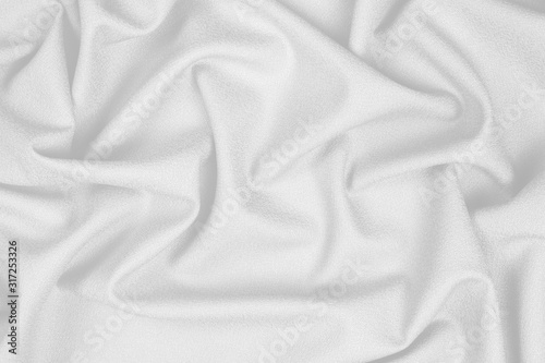 White woolen crumpled fabric with wrinkles and waves, closeup, background of crumpled tissue
