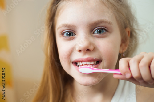 pretty blonde girl 7-8 years old brushing her teeth