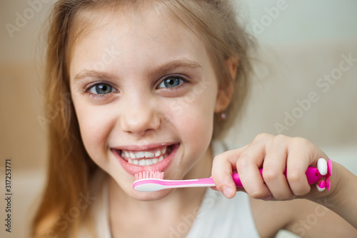 pretty blonde girl 7-8 years old brushing her teeth