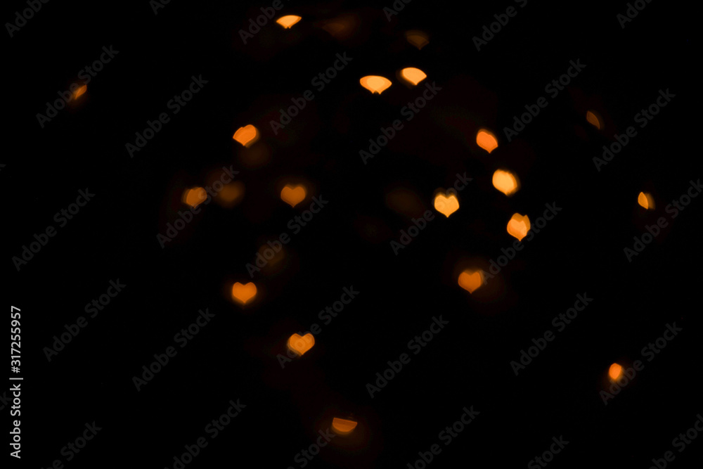 Blurred orange lights in beautiful shape of the hearts on black background. Blurred orange lights in beautiful shape of the hearts on black background.