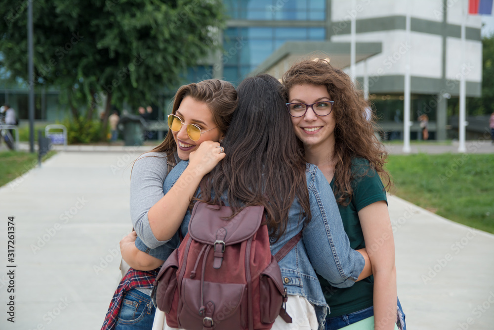 Female students hugging in front of a campus