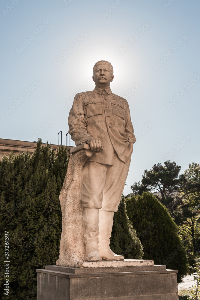 Monument to Stalin with a halo from the sun around his head on a pedestal stands on the territory of the Stalin Museum in Gori in Georgia
