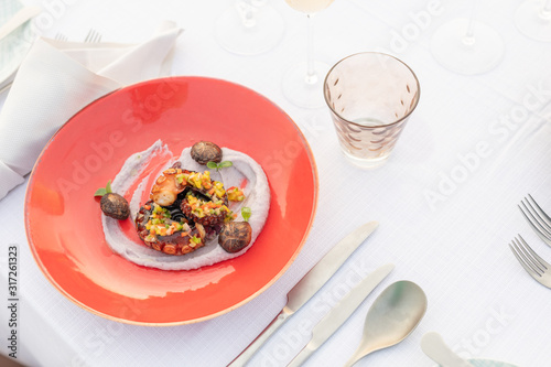 Gourmet food on elegant background. Luxury restaurant closeup. Grilled octopus on white plate served with white wine , top view. Seafood.