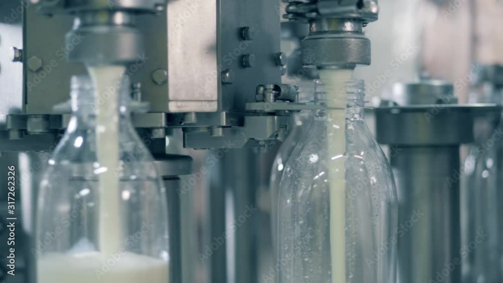 Close up of milk pouring into bottles through the plant machine Close up of milk pouring into bottles through the plant machine