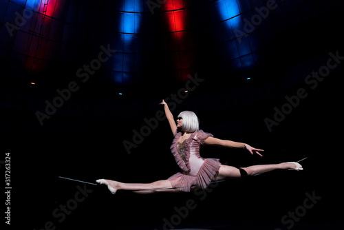 side view of beautiful aerial acrobat doing splits on rope