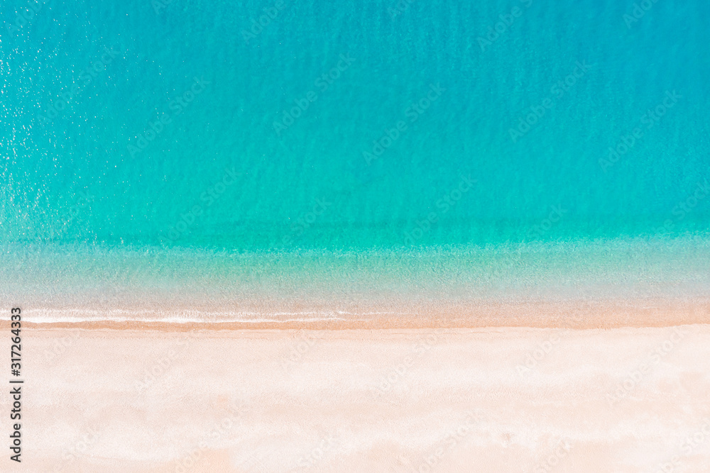 Obraz premium Flying over an empty sandy beach and beautiful emerald ocean waves. Top view landscape scene of waves rolling on an empty tropical beach