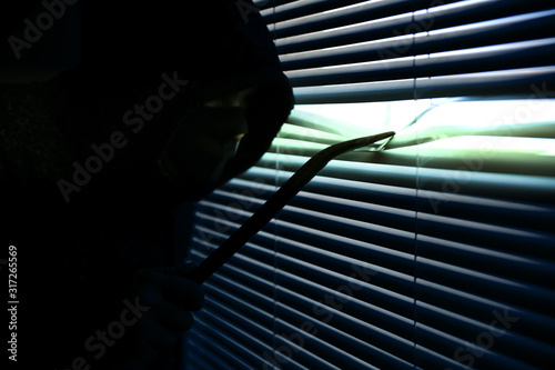 Obraz na plátně Criminal with crowbar is spying through the window