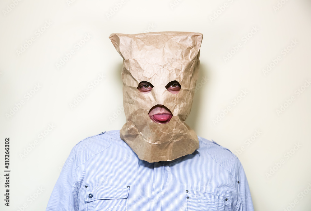 Kraft paper bag is on the man's head. Holes for eyes. Funny idea. Guy is  showing his tongue. Stock Photo | Adobe Stock