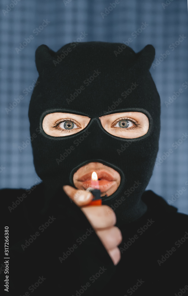 woman terrorist holding a lighter in front of her mouth. Selective focus in eyes