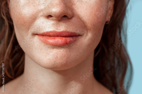 Summer Freestyle. Young woman with freckles standing isolated on blue smiling happy lips close-up