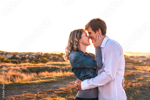 Happy young loving couple is about kiss outdoor at sunset. Concept of people, love and lifestyle.