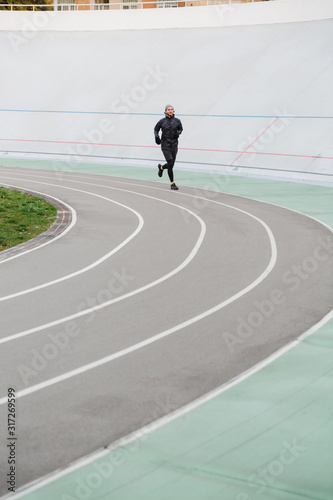 Confident young fit sportsman running on the race track