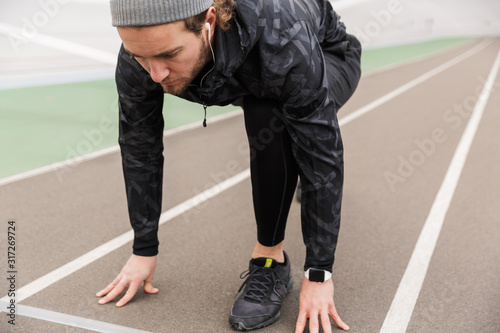 Attractive concentrated young fit sportsman getting ready to run