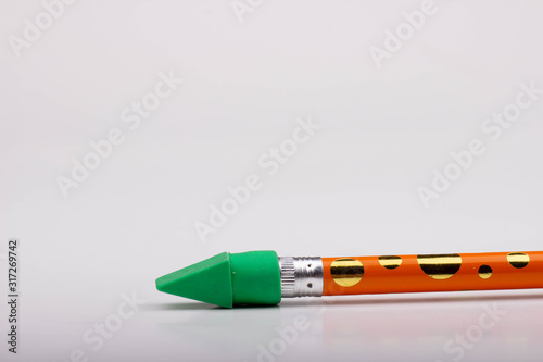 A Green Eraser on a Yellow and Gold Polka Dot Pencil photo