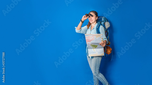 Young asian traveler happy woman in Blue shirt with backpack with and equipment for travelers Vacation with a map, on Blue color background. Travel backpack