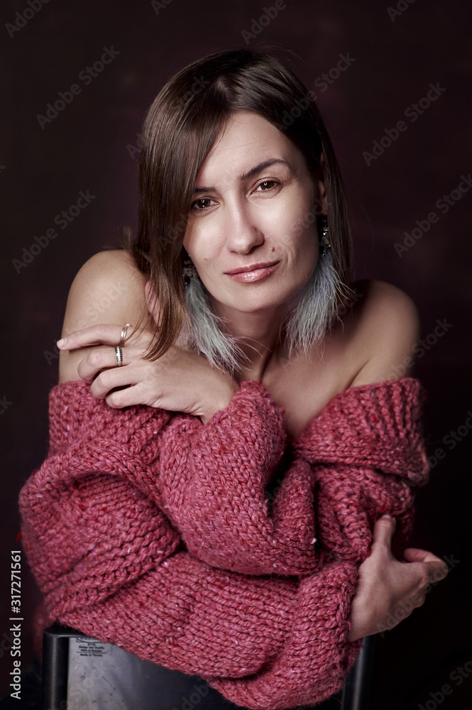 Portrait of a woman in a warm knitted sweater on a dark background Portrait of a woman in a warm knitted sweater on a dark background