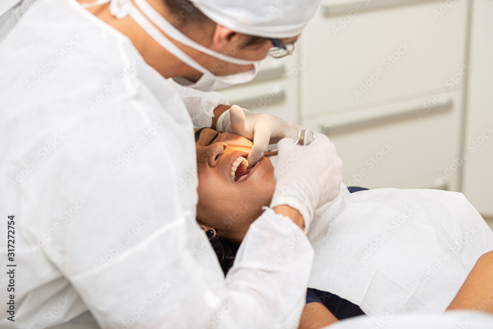 Obraz premium Young woman being seen in a dentist's office. Concept of toothache, wisdom tooth extraction, anesthesia, problems with caries or gums. Oral health care. Dentist day.