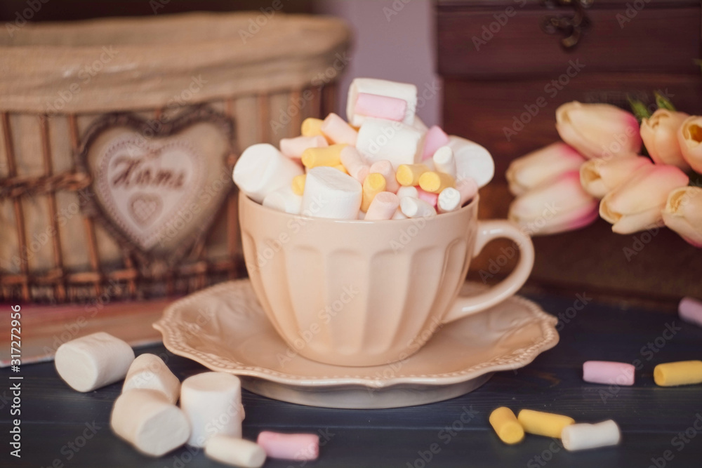 colorful marshmallows in a cup and saucer on a wooden table, tulips colorful marshmallows in a cup and saucer on a wooden table, tulips