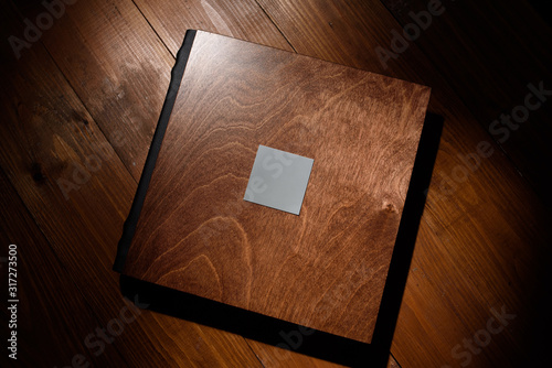 Photo book in a wooden cover on a wooden table. Hard light photo