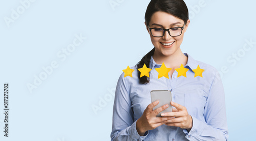 Happy Businesswoman Evaluating Mobile Application On Smartphone With Five Stars photo