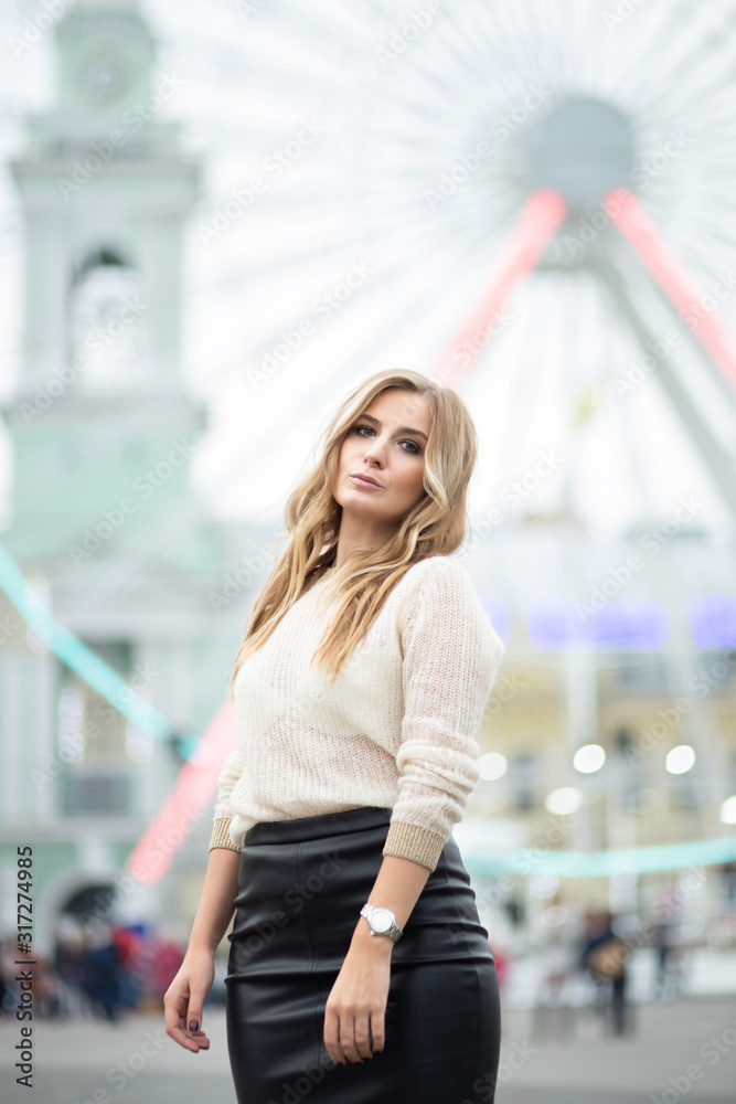 Gorgeus blonde woman in leather skirt posing on the ferris wheel background
