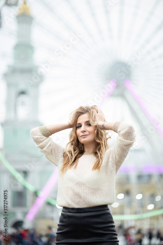 Gorgeus blonde woman in leather skirt posing on the ferris wheel background