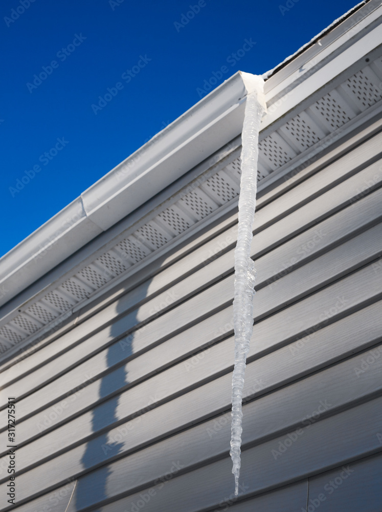 Long icicle hanging from house gutter Long icicle hanging from house gutter