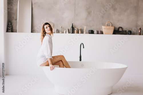 Beautiful sexy lady in elegant white shirt in a bathroom.