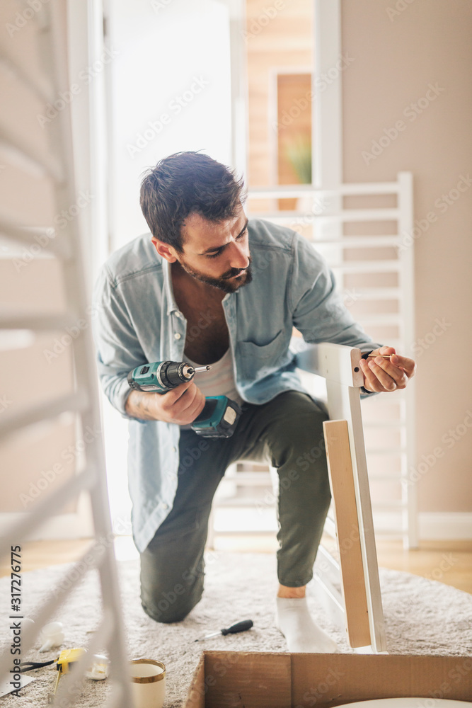 Man assembling baby crib with screwdriver.