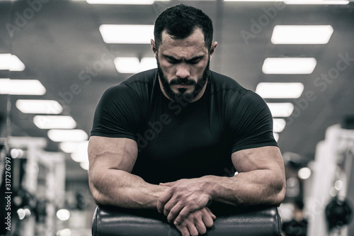 mental mind sport motivation concept of young handsome strong man with beard wearing black jersey concentration relaxation in sport gym