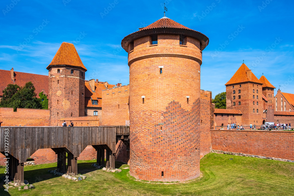 Panoramic view of the medieval Teutonic Order Castle in Malbork, Poland - external defense walls with lower castle gate tower and drawbridge over the moat