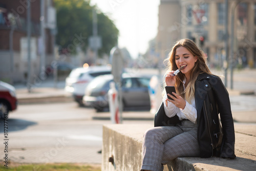 Teen girl looking at smartphone screen, urban background.