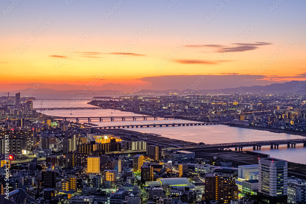Obraz premium Aerial sunset view of Osaka skyline with the river, citylight, and golden sky as seen from Umeda Sky Building.