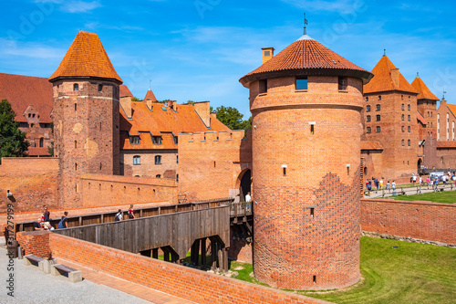 Panoramic view of the medieval Teutonic Order Castle in Malbork, Poland - external defense walls with lower castle gate tower and drawbridge over the moat