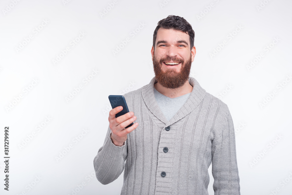 Happy man is holding his phone while smiling at the camera on white background. Happy man is holding his phone while smiling at the camera on white background.